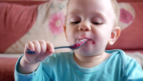 Un-atractivo-chico-de-2-años-come-una-ensalada-de-remolacha-roja.-La-cara-está-manchada-con-gachas-de-avena.-Se-sienta-en-la-mesa