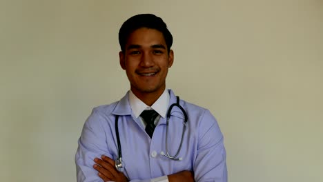 Handsome-medical-doctor-with-a-stethoscope-around-his-neck-is-looking-and-smiling-at-camera-while-standing-with-folded-arms