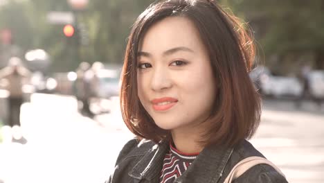 sweet-and-serene-Asian-woman-in-the-street,-smiling-sweetly-at-the-camera