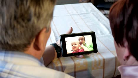 An-elderly-couple-communicates-with-their-grandchild-by-video-linking-the-tablet.-A-man-and-a-woman-are-talking-to-relatives