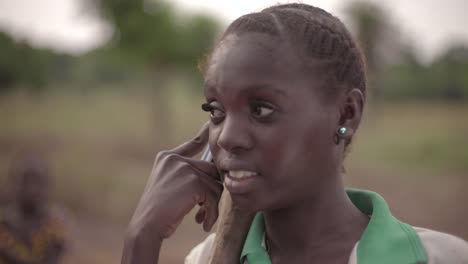 Portrait-of-a-young-African-female-farmer-spontaneously-talking-on-her-cellphone