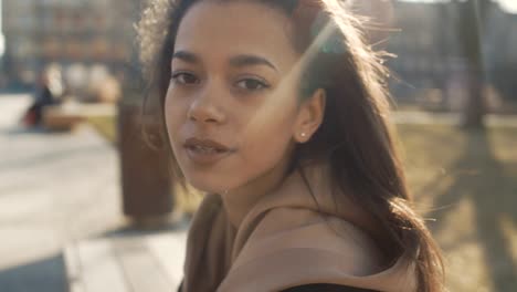 Portrait-of-young-African-American-woman-looking-to-a-camera,-outdoors.-Slow-motion.