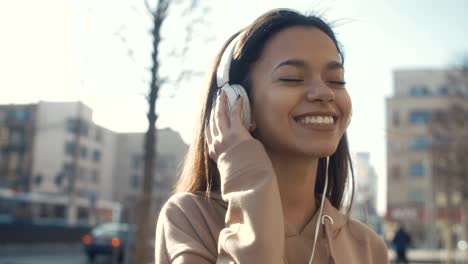 Mujer-joven-con-auriculares-disfrutando-en-una-ciudad.