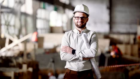 Erwachsenen-Architekt-in-einem-Helm-steht-auf-der-aktuellen-Baustelle-in-seinen-Händen-ein-Projekt-für-die-Modernisierung-einer-verlassenen-Fabrik-in-der-Stadt