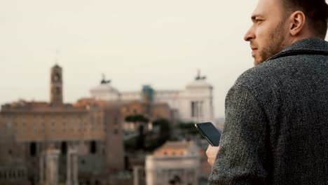 Young-attractive-businessman-use-the-smartphone-outside-in-warm-spring-day.-Handsome-male-chatting-with-friends