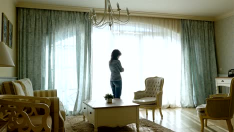 Upset-woman-going-forth-and-back-along-the-window-of-a-cozy-apartment