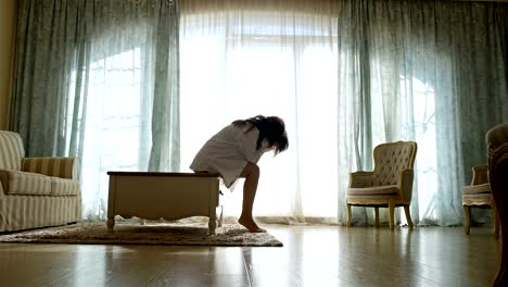 Upset-woman-in-shirt-going-forth-and-back-along-the-window-of-a-cozy-apartment