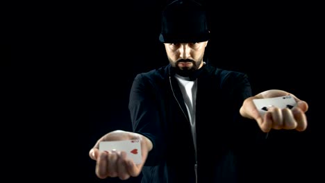 Professional-Street-Magician-in-a-Cap-Performs-Impressive-Sleight-of-Hand-Card-Trick.-Background-is-Black.