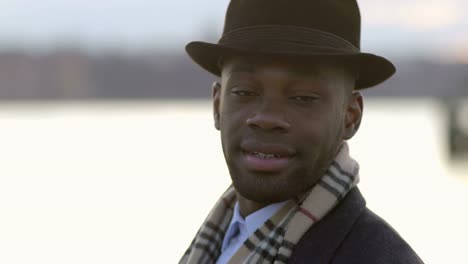 Joven-negro-a-hombres-con-gafas-de-sol,-sombrero-y-bufanda.-Disfrutar-el-día-al-aire-libre-en-la-ciudad