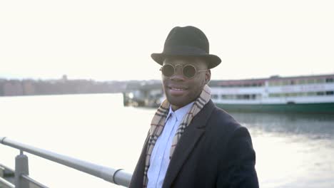 Joven-negro-a-hombres-con-gafas-de-sol,-sombrero-y-bufanda.-Disfrutar-el-día-al-aire-libre-en-la-ciudad