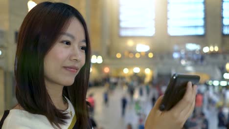 Attractive-Asian-Woman-Using-Phone-in-the-City.-Dark-Eyes-and-Dark-Hair.-Crowded-and-Urban-Background.