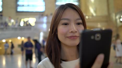 Attractive-Asian-Woman-Using-Phone-in-the-City.-Dark-Eyes-and-Dark-Hair.-Crowded-and-Urban-Background.