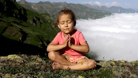 Little-cute-girl-meditating-on-top-of-mountain