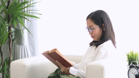 Cute-asian-woman-reading-a-book-with-smile-face-at-home.