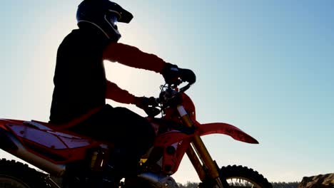 Low-Angle-Footage-of-the-Professional-Motocross-Rider-on-FMX-Motorcycle-Stands-in-the-Middle-of-the-Quarry-and-Overlooks-Extreme-Off-Road-Terrain-that-He-Gonna-Ride-Today.