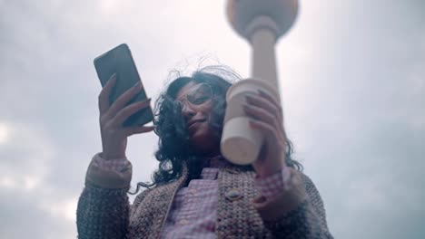 Pretty-mixed-race-girl-uses-a-smartphone-in-Berlin-Alexander-Platz-against-a-television-tower