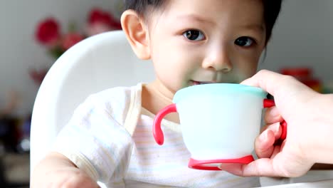 lindo-bebé-niño-bebiendo-agua-de-paja-en-la-taza-de-entrenamiento