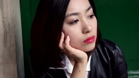 Sad-and-thoughtful-young-Chinese-woman-sitting-on-steps-in-road-steady-cam