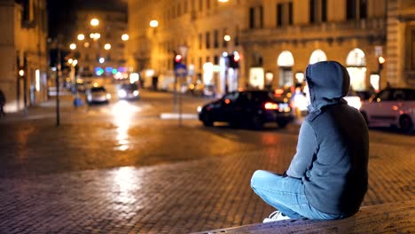 Young-person-with-hood-contemplates-the-city-at-night