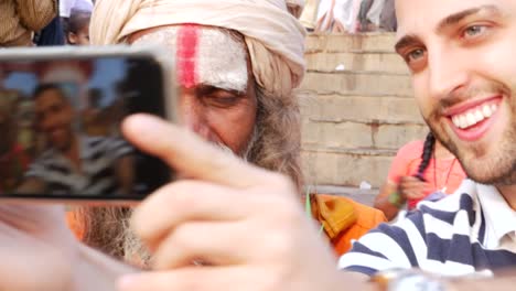 Tourist,-ein-Selbstporträt-mit-Sadhu---heiliger-Mann,-in-Varanasi,-Indien