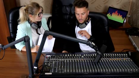 man-and-woman-in-headphones-communicate-with-each-other-beside-microphone