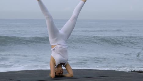 Frau-üben-Handstand-an-Küste