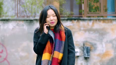 Smiling-relaxed-asian-woman-talking-by-phone--outdoor