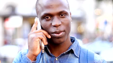 handsome-black-african-man-talking-by-phone-in-the-street--close-up