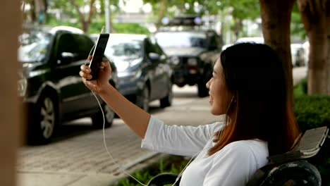 Beautiful-woman-having-video-chat-using-smartphone-outdoors-at-public-park.