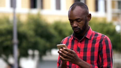 black-african-man-typing-on-smartphone-in-the-street