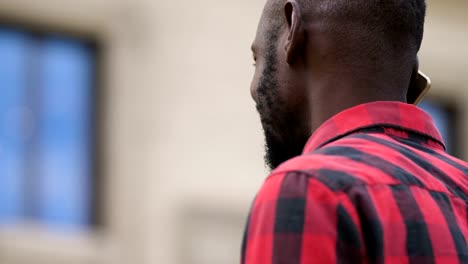 Smiling-black--young-man-talking-by-phone-in-the-street