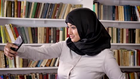 Joven-musulmanes-mujeres-bonitas-en-hijab-tomar-selfie-entonces-mirando-en-el-teléfono-y-viendo-fotos-en-el-teléfono-en-la-biblioteca,-sonriendo