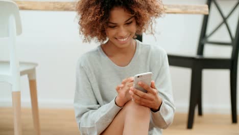 Beautiful-young-afro-american-woman-texting-on-mobile-phone-at-home.