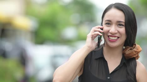 Young-beautiful-Asian-businesswoman-talking-on-the-phone-in-the-streets-outdoors