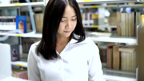 4K-Slow-motion-:-Asian-female-college-student-reading-book-in-the-library,-Tilt-up-shot