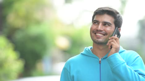 Young-happy-Persian-man-talking-on-the-phone-outdoors