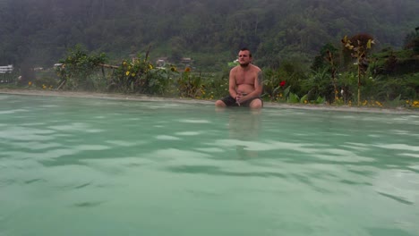 Un-hombre-se-sienta-en-el-borde-de-una-piscina-con-agua-termal-caliente