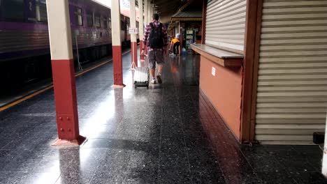 Tourists-walk-dragging-luggage-in-the-train-station.-Work-and-travel-concept.