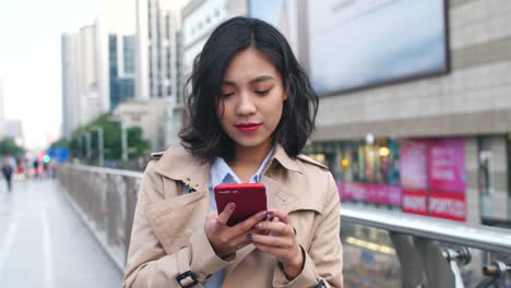 Una-bonita-asiática-joven-uso-teléfono-móvil-en-la-ciudad