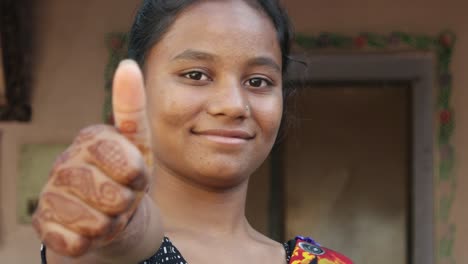 Mitte-Schuss-von-jungen-schönen-Indianerin-Punkte-akzeptieren-Daumen-hoch-für-Genehmigung-Geschmack-sicheren-Spaß-Freude-an-der-Kamera-mit-ihr-Henna-Tattoo-hand-lächelnd-positive-zuversichtlich-Führer-Überzeugung-statische-Schuss