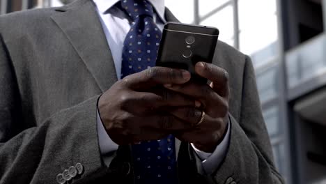 Busy-Black-business-man-typing-on-his-smartphone--close-up