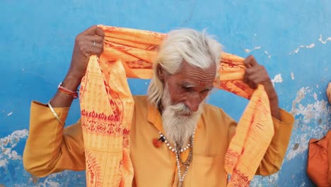 Indischen-Sadhu-Safran-Heilige-Kleidung-anziehen-einen-Turban-vor-einer-blauen-Wand