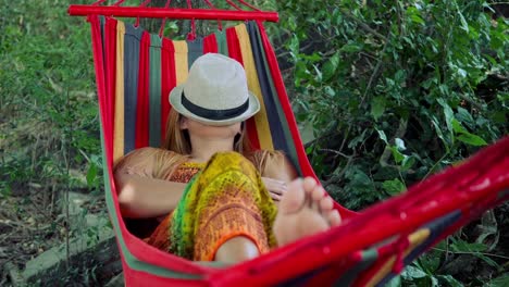 Mujer-joven-durmiendo-en-hamaca-con-sombrero-que-cubre-la-cara