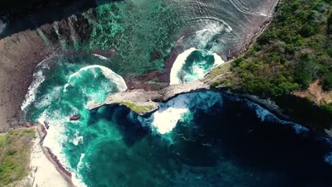 Aerial-view-by-drone-4k-camera.-Rocks-in-a-blue-sea-lagoon-with-breaking-waves.