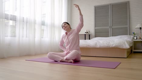 mujer-se-sienta-en-la-estera-de-yoga-y-estiramiento-brazos