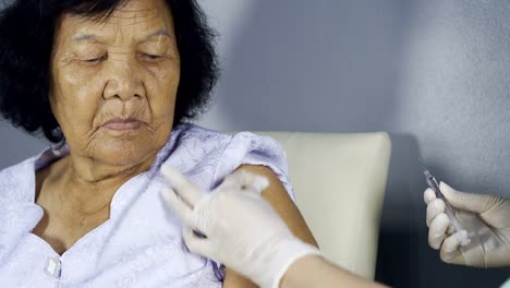 Doctor-giving-vaccine-injection-into-senior-woman-shoulder