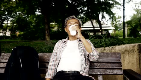 Asiatische-senior-Mann-sitzt-im-Park-einen-Kaffee-und-nutzen-Smartphone