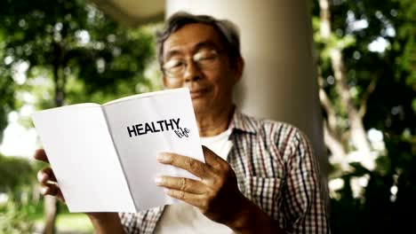 Asian-senior-man-reading-Healthy-Life-book-alone-in-the-park