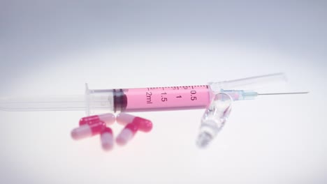 Syringe-with-pink-liquid.-Pharmaceutical-pills-and-medical-glass-ampule