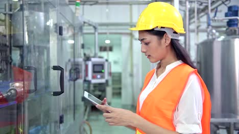 Mujer-ingeniero-industrial-en-el-trabajo-en-la-fábrica.-Hermosa-joven-ingeniero-chino-trabajando-en-fábrica-grande.-Con-casco-y-chaqueta.-Máquina-automática-de-alta-tecnología-en-segundo-plano.